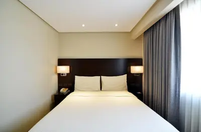 a bedroom with a large white bed and a window at Pearl Garden Hotel in Manila
