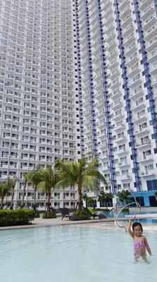 a little girl standing in a pool in front of a large building at Jazz Hunter Residence in Manila