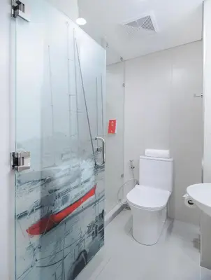 a bathroom with a toilet and a glass shower door at Red Planet Manila Binondo in Manila