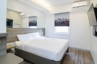 a bedroom with a white bed and a television at Red Planet Manila Bay in Manila