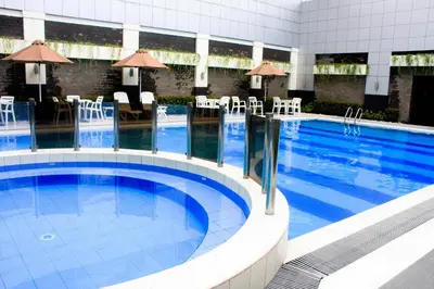 a swimming pool in a hotel with tables and chairs at Manila Grand Opera Hotel in Manila