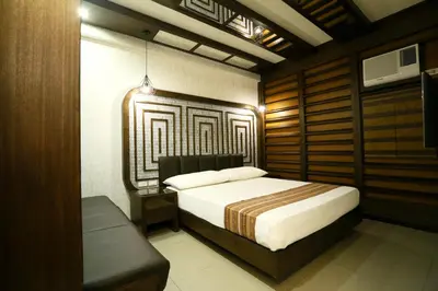 a bedroom with a bed and a bench in it at Hotel Ava Malate in Manila