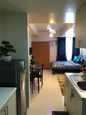 a kitchen and living room with a table and a bed at Centropolis in Manila