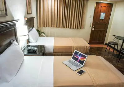 a hotel room with two beds and a laptop on a table at Fersal Hotel - P. Tuazon Cubao in Manila