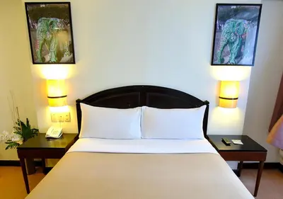 a bedroom with a bed with two tables and two lamps at Fersal Hotel Neptune Makati in Manila
