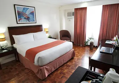a hotel room with a large bed and a desk at Fersal Hotel Neptune Makati in Manila
