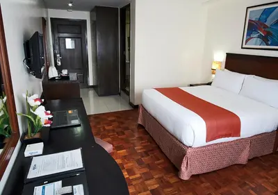 a hotel room with a bed and a desk with a laptop at Fersal Hotel Neptune Makati in Manila