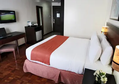 a hotel room with a bed and a desk and a television at Fersal Hotel Neptune Makati in Manila