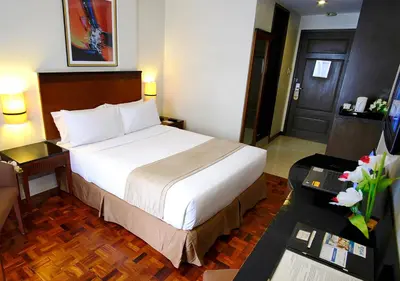 a hotel room with a large bed and a desk at Fersal Hotel Neptune Makati in Manila