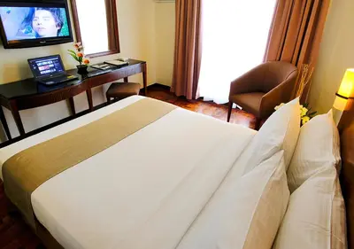 a hotel room with a bed and a desk and a television at Fersal Hotel Neptune Makati in Manila