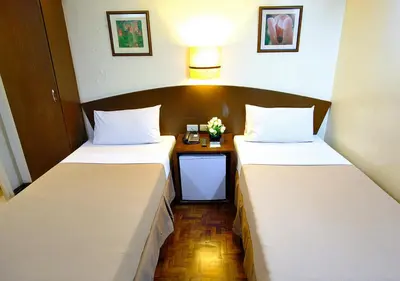 a room with two beds and a table with flowers at Fersal Hotel - Manila in Manila