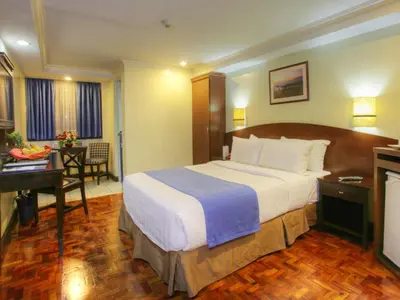a hotel room with a large bed and a desk at Fersal Hotel - Manila in Manila