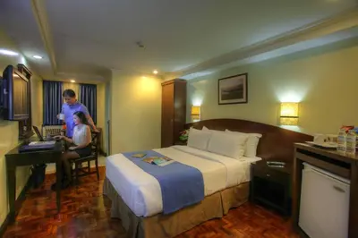 a hotel room with a bed and a man and a child at Fersal Hotel - Manila in Manila