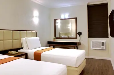 a hotel room with two beds and a mirror at Rothman Hotel in Manila