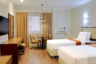 a hotel room with two beds and a table at Rothman Hotel in Manila