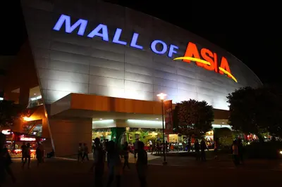 a mall of asia with people standing outside at night at Riviera Mansion Hotel in Manila