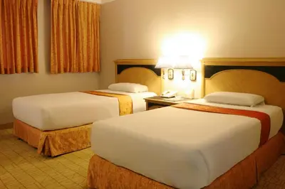 a hotel room with two beds and a lamp at Riviera Mansion Hotel in Manila