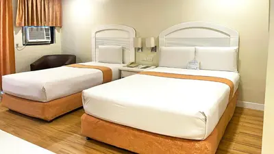 a hotel room with two beds and a chair at Riviera Mansion Hotel in Manila