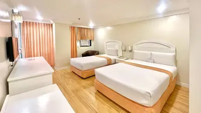 a hotel room with two beds and a television at Riviera Mansion Hotel in Manila
