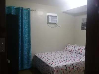 a bedroom with a bed and a air conditioner on the wall at Mmr in Manila