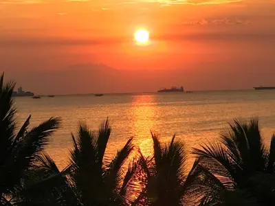 a sunset over the ocean with palm trees in the foreground at BEST Q CONDO w/ Great View in Manila