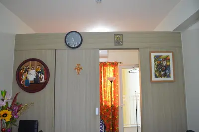 a clock on a wall above a door with a cross at Jovic's Condo at Breeze Residences. in Manila