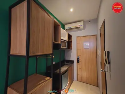 a small kitchen with green walls and wooden cabinets at Skyloft Hotel in Manila