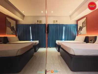 two beds in a room with blue curtains at Skyloft Hotel in Manila