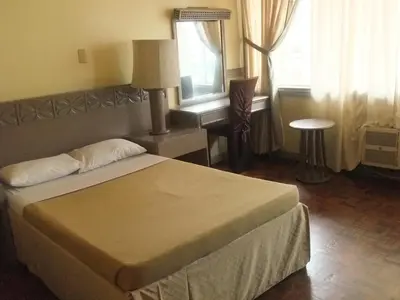 a bedroom with a bed and a desk and a window at Manila Manor Hotel in Manila