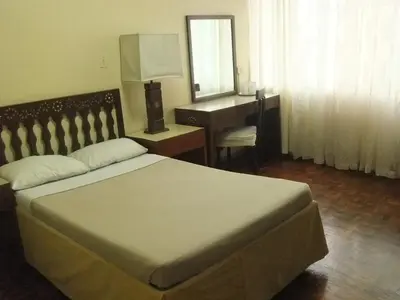 a bedroom with a bed and a desk and a mirror at Manila Manor Hotel in Manila