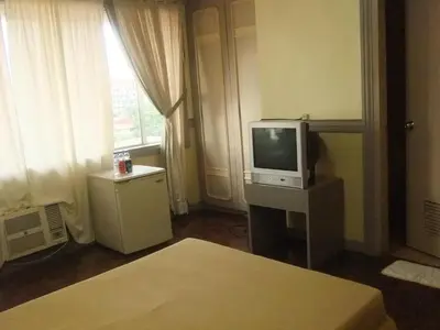 a living room with a television and a bed at Manila Manor Hotel in Manila