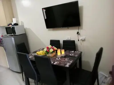 a dining room table with chairs and a television on the wall at SMDC Breeze Residences by Dominga in Manila