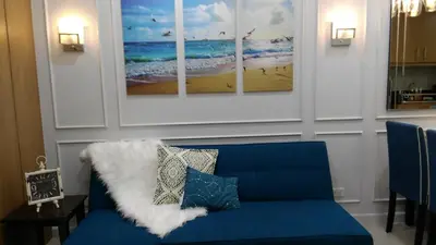 a blue couch in a living room with paintings on the wall at Shell Residence Manila in Manila