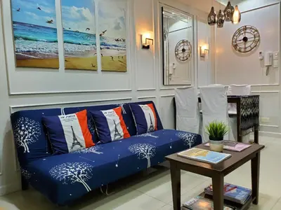 a living room with a blue couch and a table at Shell Residence Manila in Manila