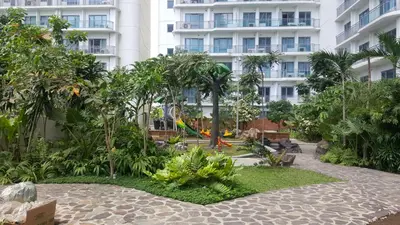 a garden in front of a large building at Modern Luxury Lower Penthouse Unit in Manila