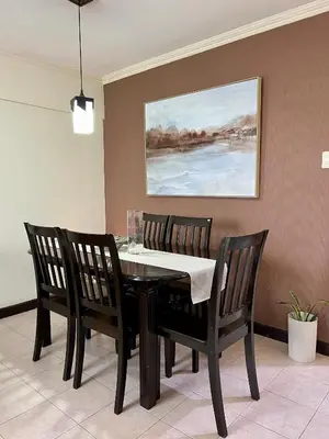 a dining room table with four chairs and a painting at East Ortigas Mansions by MA in Manila