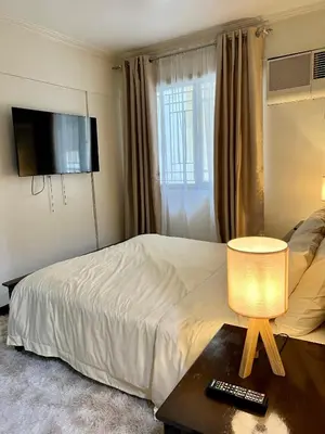 a hotel room with a bed and a television at East Ortigas Mansions by MA in Manila