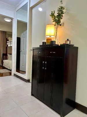 a black cabinet with a lamp on top in a room at East Ortigas Mansions by MA in Manila