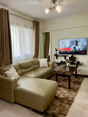 a living room with a couch and a flat screen tv at East Ortigas Mansions by MA in Manila