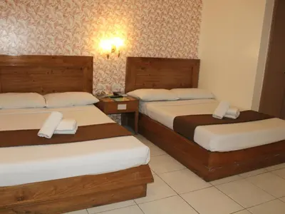 a hotel room with two beds and two tables at Rosas Garden Hotel in Manila