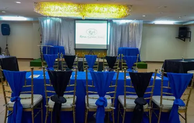 a room with blue tables and chairs and a screen at Rosas Garden Hotel in Manila