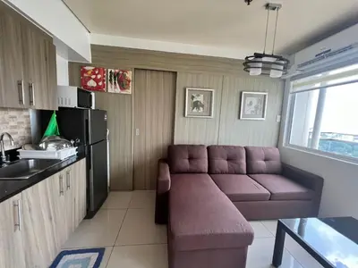 a living room with a couch and a kitchen at De Luxe, Standard and Studio Suites -The Breeze Residences-close to Airport,Mall of Asia, US Embassy in Manila