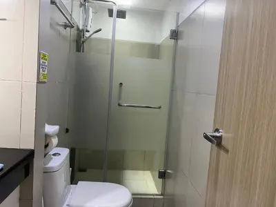 a bathroom with a shower with a toilet and a glass door at De Luxe, Standard and Studio Suites -The Breeze Residences-close to Airport,Mall of Asia, US Embassy in Manila