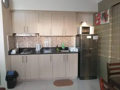a kitchen with white cabinets and a stainless steel refrigerator at De Luxe, Standard and Studio Suites -The Breeze Residences-close to Airport,Mall of Asia, US Embassy in Manila
