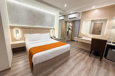 a hotel room with a large bed and a desk at City Garden Hotel Makati in Manila