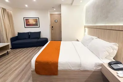 a hotel room with a bed and a blue couch at City Garden Hotel Makati in Manila