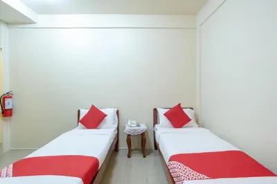 two beds in a room with red and white pillows at Conrado's Apartelle in Manila