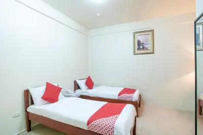 two beds in a small room with red and white pillows at Conrado's Apartelle in Manila