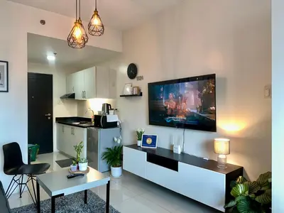 a living room with a table and a kitchen at JR Studio Luxe 1824 at Princeton Residences in Manila