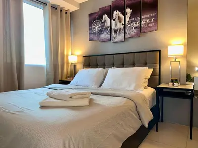 a bedroom with a large white bed with two lamps at JR Studio Luxe 1824 at Princeton Residences in Manila